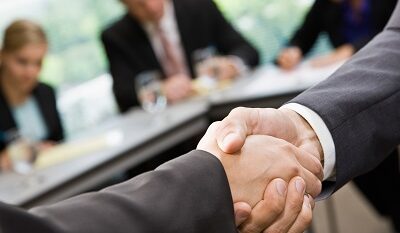 Close up of businessmen shaking hands in conference room