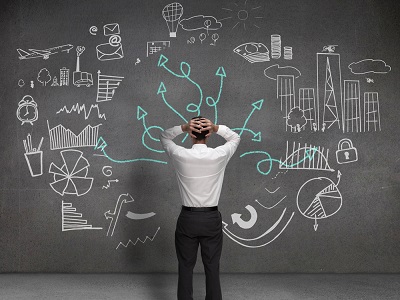 Businessman looking at drawings of arrows and charts on the wall